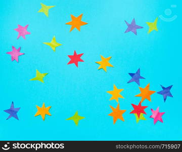collage of multicolored stars cut from papers on blue turquoise pastel paper