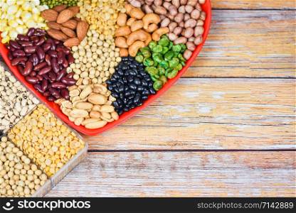 Collage various beans mix peas agriculture of natural healthy food for cooking ingredients / Set of different whole grains beans and legumes seeds lentils and nuts colorful on red heart background