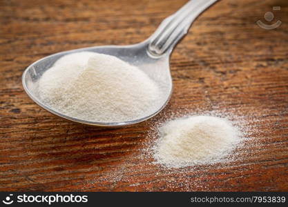 collagen protein powder on a tablespoon against rustic wood