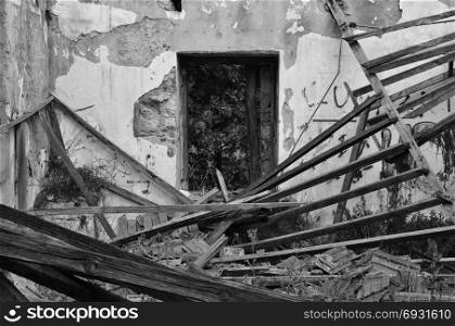 Collapsed roof chipped interior walls and window of an abandoned house. Black and white.