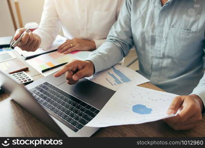 Colleagues are talking about the results in the documents on hand and compared with the financial information on the laptop screen.