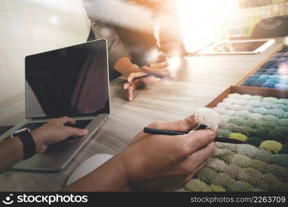 colleagues interior designers discussing data with new modern computer laptop and pro digital tablet with sample material on wooden desk as concept