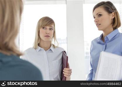 Colleagues listening to mature businesswoman in meeting at office