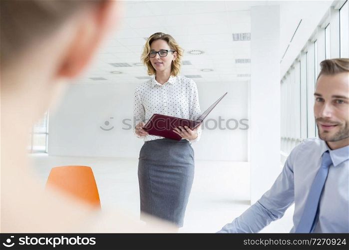 Colleagues looking at businesswoman during meeting in new office