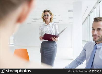 Colleagues looking at businesswoman during meeting in new office