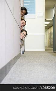 Colleagues peering around cubicle