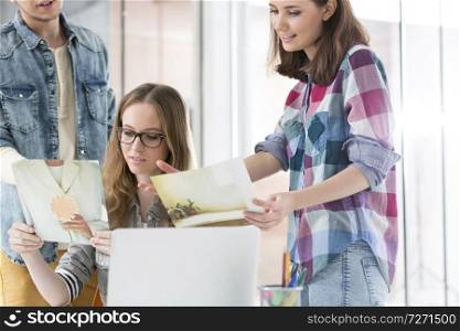 Colleagues showing photographs to businesswoman in office
