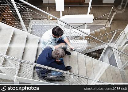 Colleagues sitting on stairway looking at smartphone
