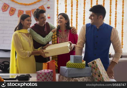 Colleagues standing together in office with gift boxes in front on the occasion of Diwali celebration. 