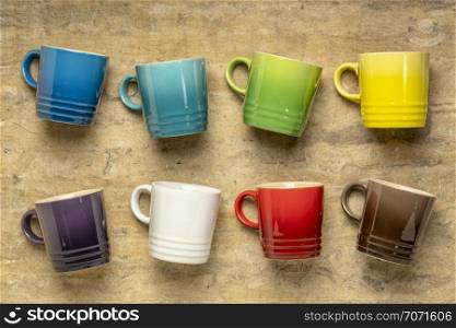 collection of colorful stoneware coffee cups against textured handmade bark paper