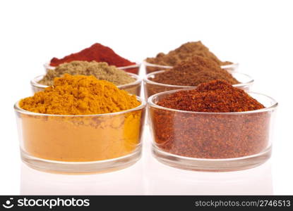 collection of indian spices (cumin, coriander, paprika, garam masala, curcuma, chili powder) on glass cups isolated on white background