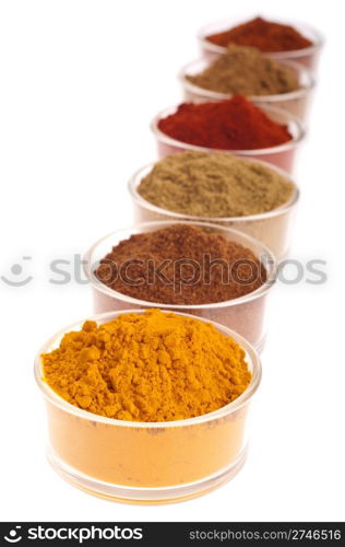 collection of indian spices (cumin, coriander, paprika, garam masala, curcuma, chili powder) on glass cups isolated on white background (shallow DOP, focus on first)