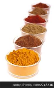 collection of indian spices (cumin, coriander, paprika, garam masala, curcuma, chili powder) on glass cups isolated on white background (shallow DOP, focus on first)