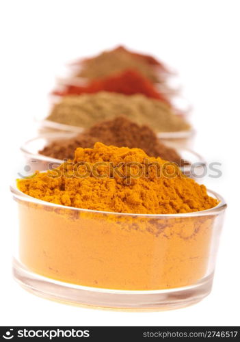 collection of indian spices (cumin, coriander, paprika, garam masala, curcuma, chili powder) on glass cups isolated on white background (shallow DOP, focus on first)