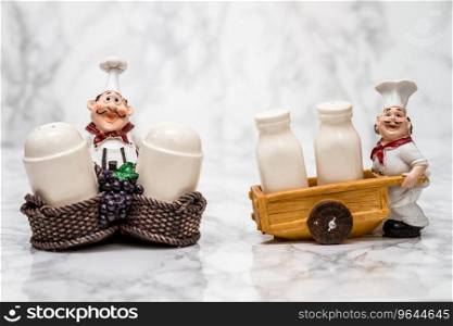 Collection of statuettes of cooks with shakers on white marble background
