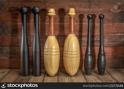 collection of steel, wooden and plastic Indian clubs against rustic, weathered wood background - home gym and functional fitness concept