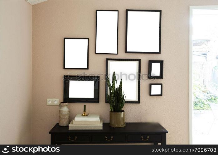 collection of various blank black frames on wall with modern decoration, green plant in a lovely home retro design. collection of various blank black frames on wall with modern decoration, green plant in a lovely home