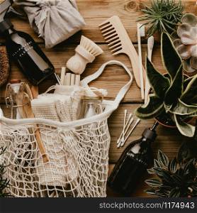Collection of various succulent plants and Mesh market bag with bamboo cutlery, reusable bottles, eco cotton bags, house cleaners and bathroom accessories on wooden background. Sustainable lifestyle. Plastic free concept.