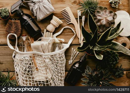 Collection of various succulent plants and Mesh market bag with bamboo cutlery, reusable bottles, eco cotton bags, house cleaners and bathroom accessories on wooden background. Sustainable lifestyle. Plastic free concept.