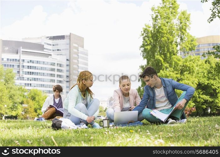 College friends studying while using laptop at campus