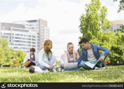 College friends studying while using laptop at campus