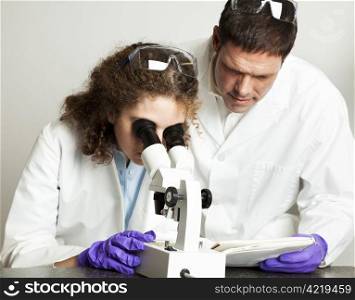 College (or high school) student working in science lab. Her teacher is looking over her notes.