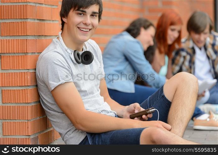 College student boy sitting on ground with friends hanging out