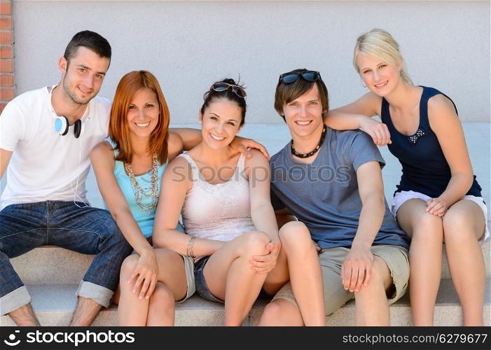 College student friends sitting in row on steps smiling camera