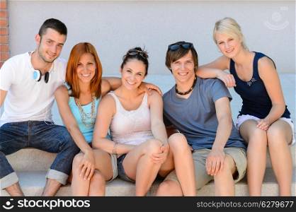 College student friends sitting in row on steps smiling camera