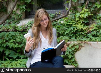 College student reading a book and enjoying a beverage