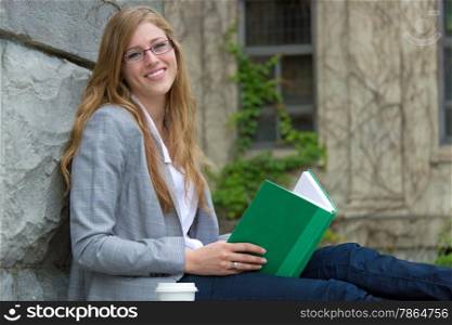 College student reading a book outdoors