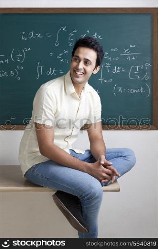 College student sitting on a table smiling