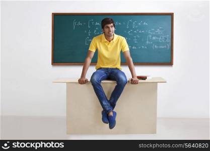 College student sitting on a table smiling