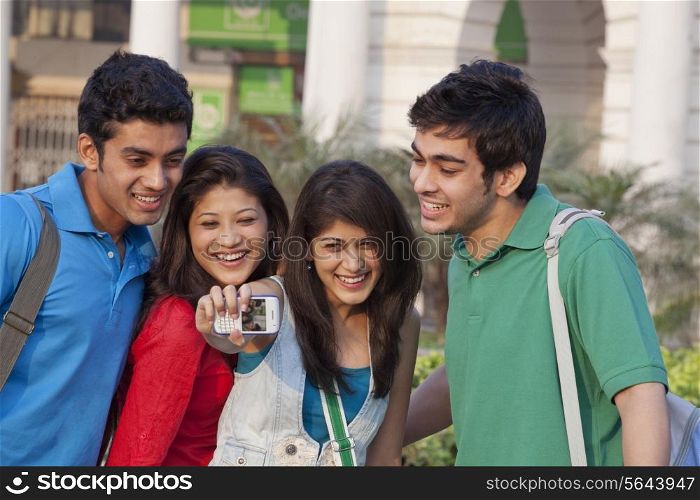 College students photographing themselves through mobile phone