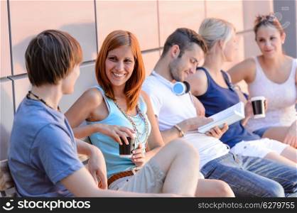 College students sitting in row modern wall outside summer campus