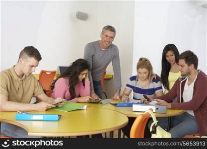 College Students With Tutor Using Digital Devices