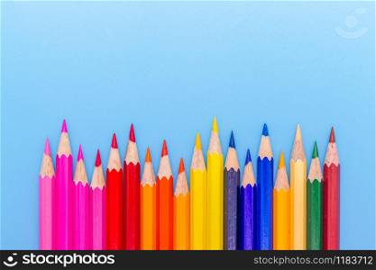 Collor wooden pencils in row isolated on bluebackground. Top view with copy space.