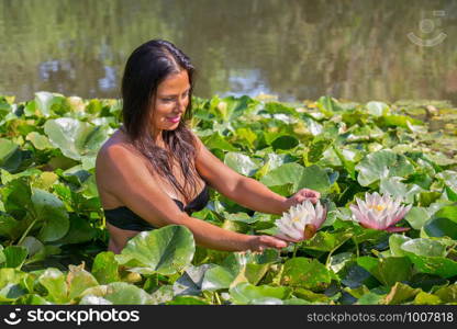 Colombian woman holding water lily in natural water of dutch pond