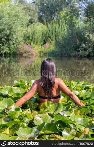 Colombian woman walking through water plants in dutch pond