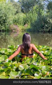 Colombian woman walking through water plants in dutch pond