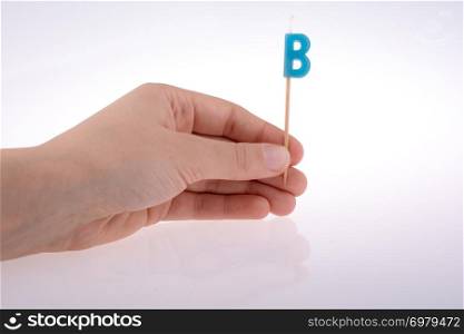 Color candle in hand on sticks writes the letter B