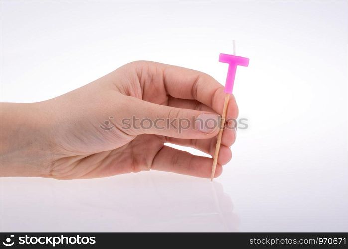 Color candle in hand on sticks writes the letter T
