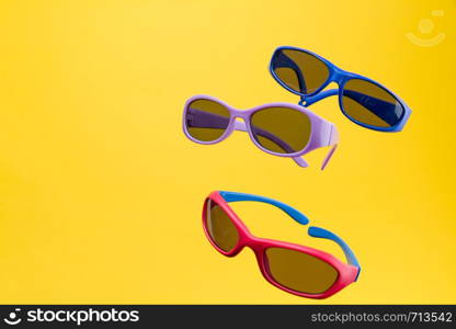 Color Children sunglasses isolated on yellow background. Concept of sun protection summer and vacation. Front view with copy space. Studio Shot