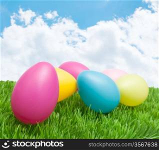 Color Easter Eggs in Grass under Sunny Blue Sky