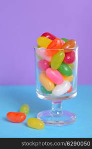 color Jelly Beans in glass on lila background