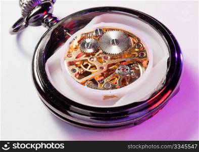 Color lights illuminate an old pocket watch with the mechanism