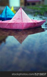 Color paper boat in a puddle
