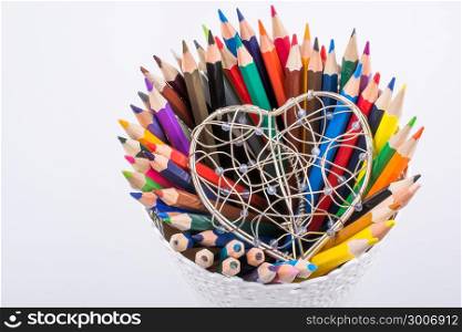 Color Pencils and heart shaped metal wire cage on a white background