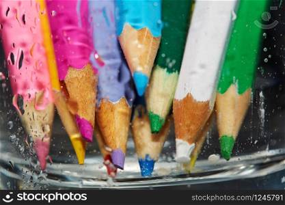 Color pencils behind the wet glass. Close-up photo
