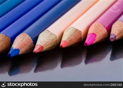 Color pencils in diagonal formation and their reflection on underlying surface. Shot at close-up
